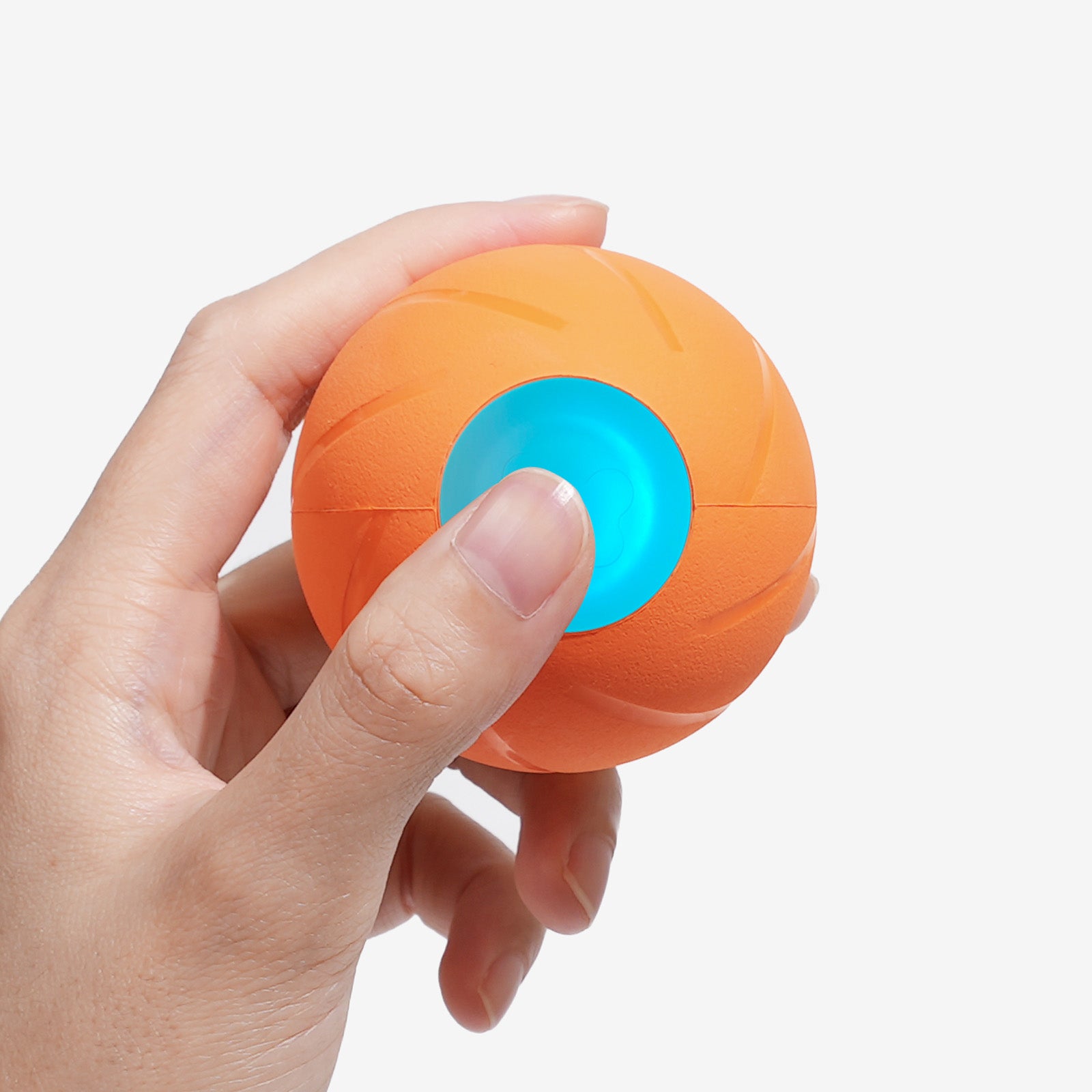 Hand holding orange Wicked Ball SE smart dog toy, with a blue light